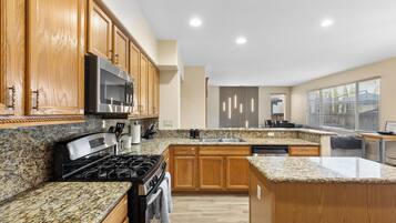 A modern kitchen with granite countertops, wooden cabinets, stainless steel appliances, and a built-in dishwasher.