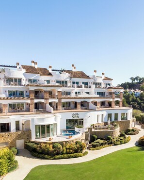 Ein mehrstöckiges Hotel mit Spa-Bereich, Außenpool und gepflegten Gärten.