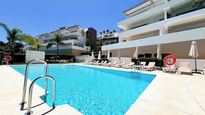 A swimming pool with lounge chairs and umbrellas, surrounded by modern buildings. - Exclusive La Cala Resort Apartment | Mijas - Pass the Keys (Mijas)