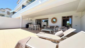 Ein moderner Außenbereich mit Pool, Liegestühlen, Esstisch und einer Couch.