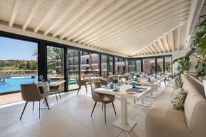 A spacious indoor dining area with a pool view, modern furniture, and large windows. - Exclusive La Cala Resort Apartment | Mijas - Pass the Keys (Mijas)