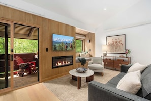 Ein modernes Wohnzimmer mit Kamin, Fernseher und einer Couch.