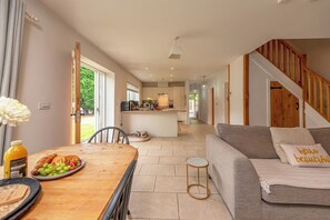 A spacious living area with a wooden dining table, a grey sofa, and a staircase. - Charming Countryside Barn | Rural Shropshire - Pass the Keys (Newport)