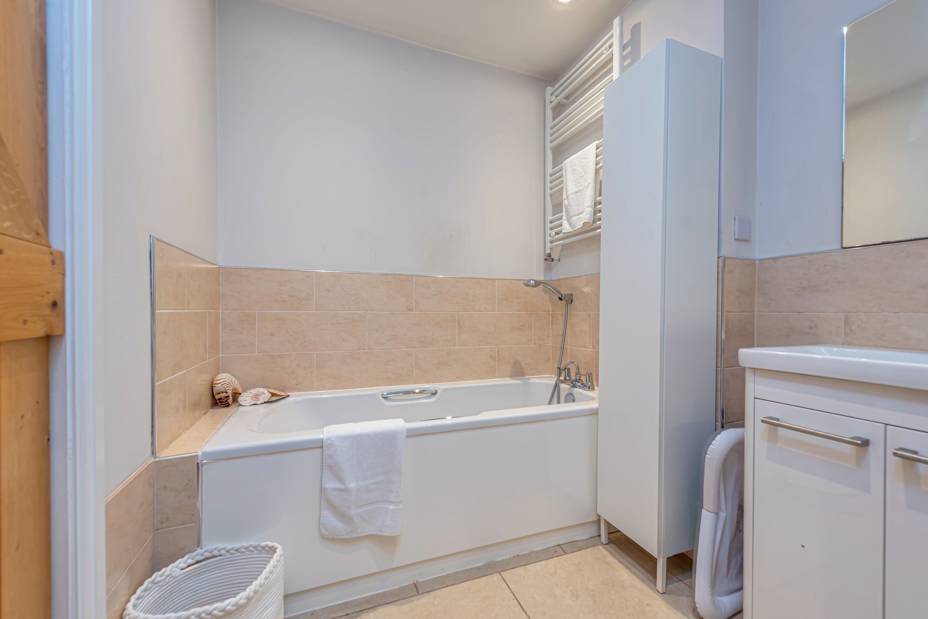 A modern bathroom with a bathtub, a towel rack, and a sink.