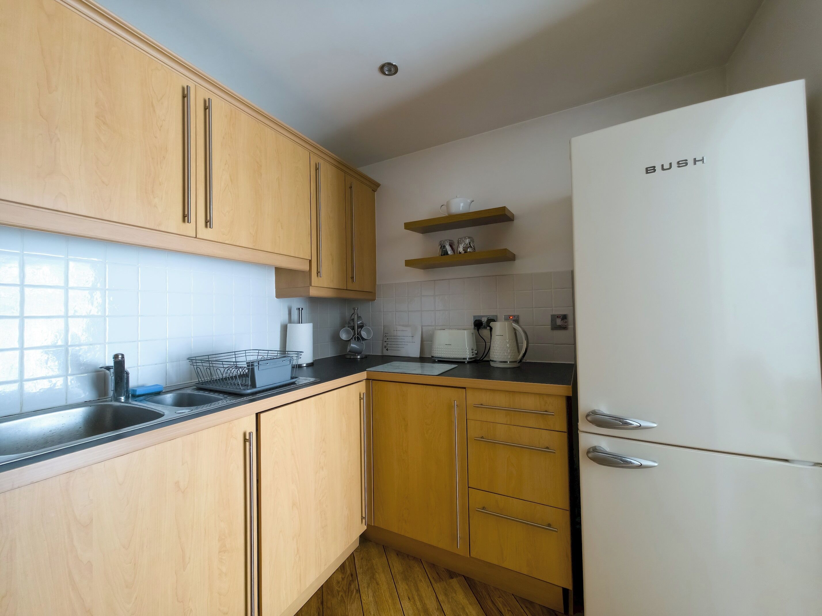 A kitchen with wooden cabinets, a white refrigerator, a coffee maker, and a kettle.
