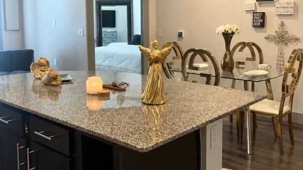 Eine Küche mit Granit-Arbeitsplatten, goldenen Dekorationselementen und moderner Pendelleuchten.