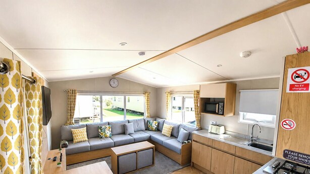 Interior compacto de autocaravana con sofá, kitchenette y televisor.