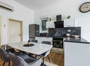 A modern kitchen with a marble countertop, black cabinets, and a built-in oven. - Modern Apartment Near The Sea (Podstrana)