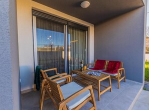 A balcony with wooden furniture, a table, and a red throw blanket.
