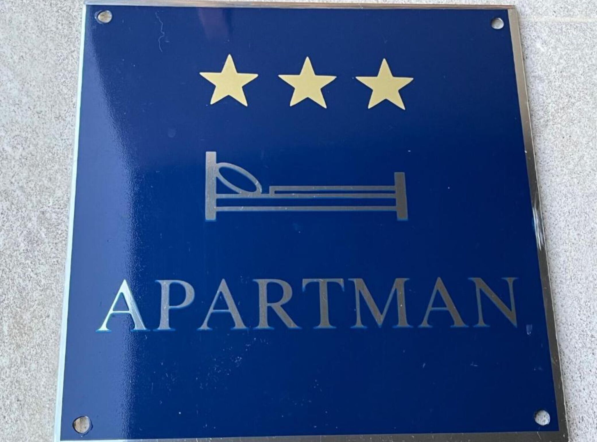 Un panneau avec trois étoiles et le mot « APARTMAN », indiquant un hôtel ou un établissement proposant des hébergements.