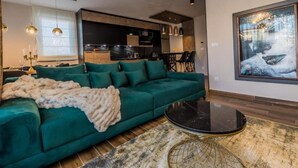 A modern living room with a green sofa, a round coffee table, and a large window.