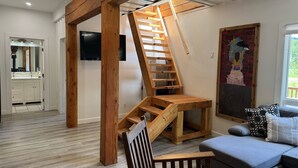 A modern interior with a wooden staircase, a gray sofa, and a painting on the wall. - Unique Container home. 10 min from town. Stunning Mountain Views! (Golden)