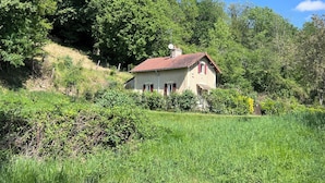 A house with a red roof, surrounded by lush greenery and trees.