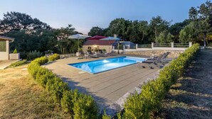 A swimming pool with lounge chairs, a covered seating area, and a stone wall. - Four Bedroom Villa with Outdoor Pool (Studenci)