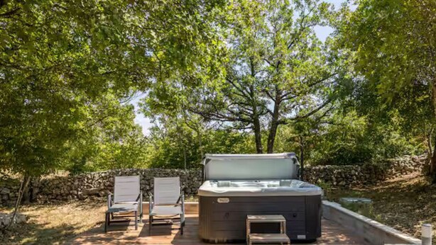A hot tub with two lounge chairs and a stone wall in a wooded area. - Four Bedroom Villa with Outdoor Pool (Studenci)