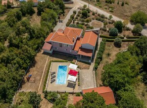 Eine Vogelperspektive auf ein großes Haus mit Swimmingpool, umgeben von Grünflächen und einem gepflegten Garten.