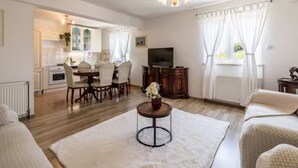 A living room with a sofa, a coffee table, a TV, and a dining area with chairs and a table. - Four Bedroom Villa with Outdoor Pool (Studenci)