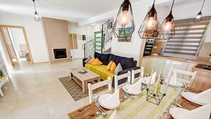 Un salon moderne avec un canapé, une table à manger dressée pour un repas et un escalier menant à un autre niveau.