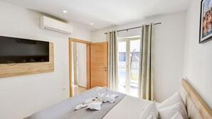 Une chambre d’hôtel comprenant un lit, un téléviseur à écran plat fixé au mur, une porte coulissante donnant sur un balcon et un tableau encadré accroché au mur.