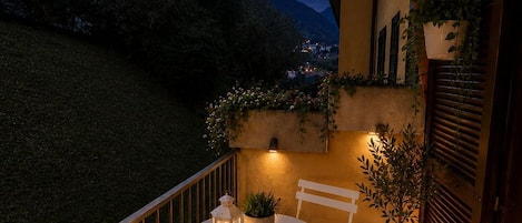 A terrace with a table and chairs, potted plants, and a view of the surrounding landscape.
