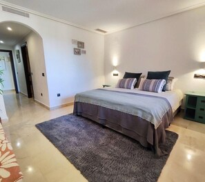 Une chambre à coucher avec un lit, une table de chevet, un tapis et un couloir.