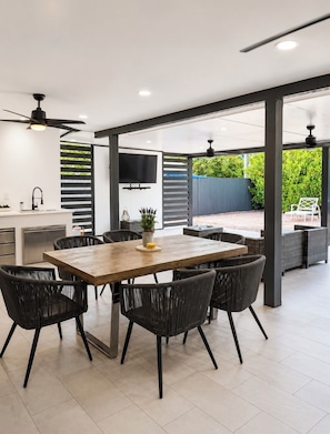 Una cocina moderna con comedor, televisor y vistas al jardín.