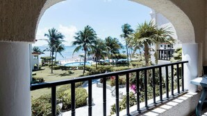 Ein Balkon mit Blick auf ein Schwimmbad, Palmen und einen Strand.