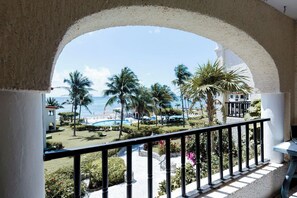 Ein Balkon mit Blick auf ein Schwimmbad, Palmen und einen Strand.