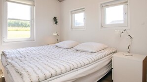 Ett sovrum med en säng, två sänglampor och tre fönster.