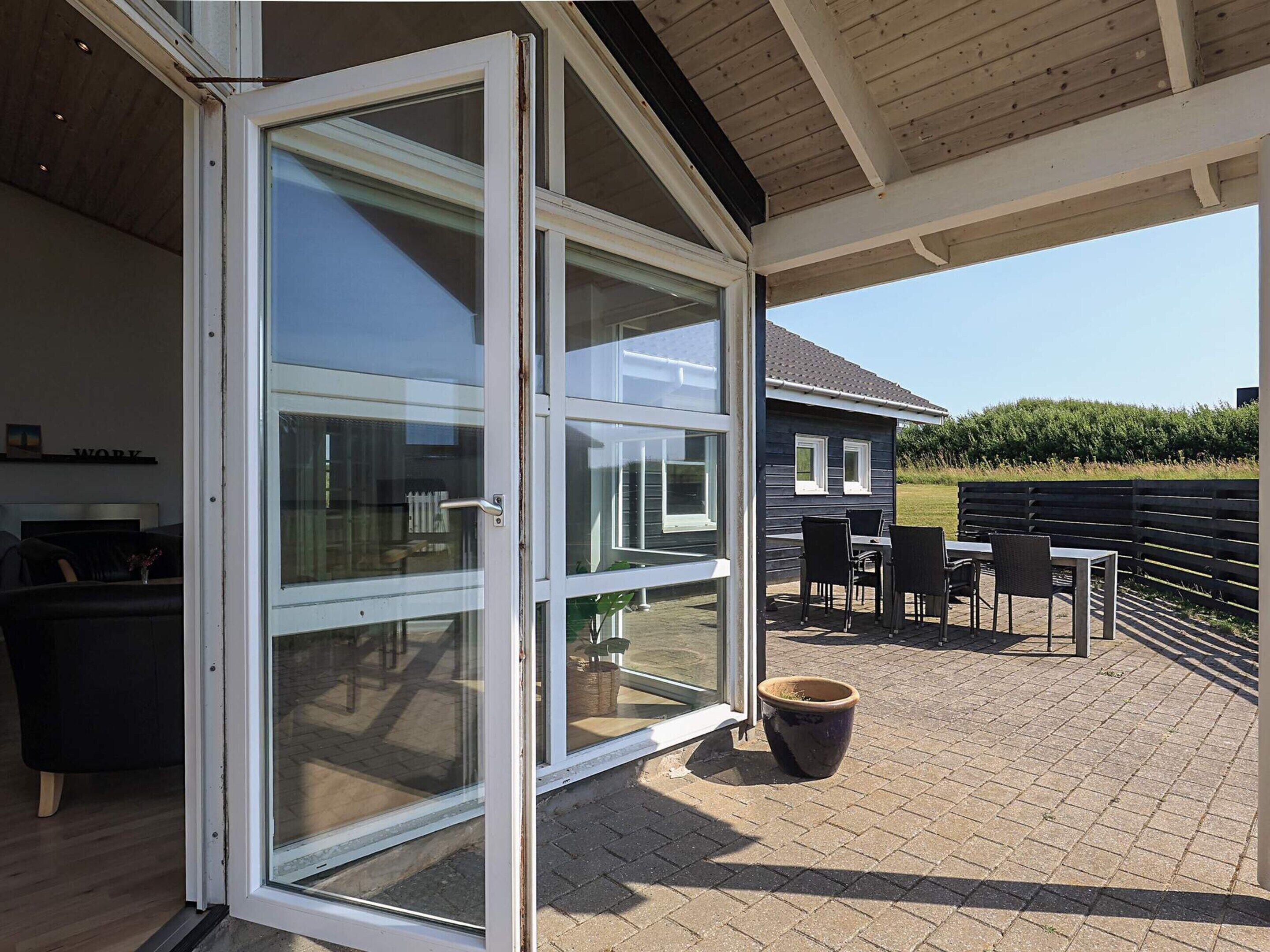 A modern house with a glass door leading to an outdoor patio area.