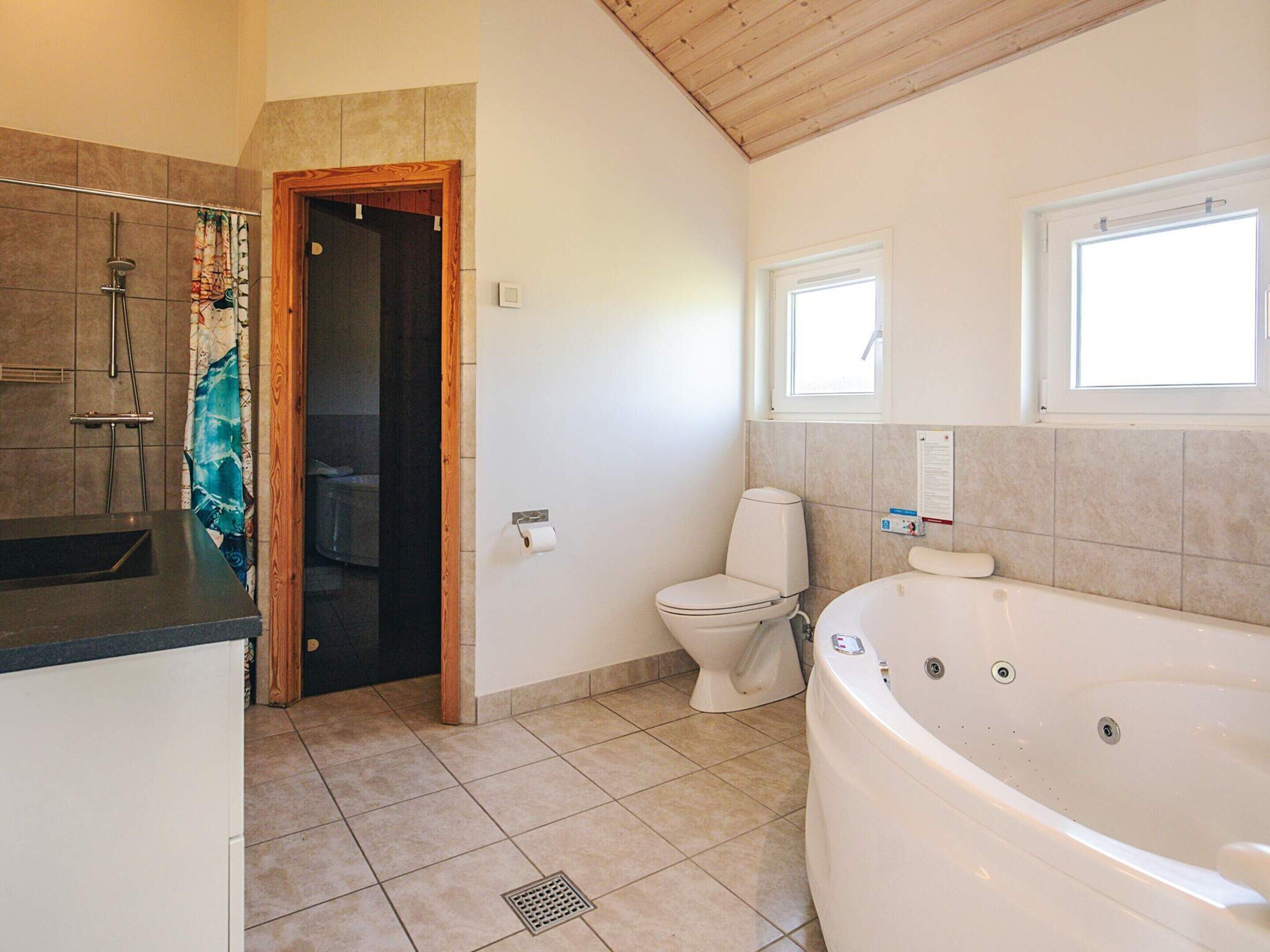 Un baño con bañera, inodoro, ducha y ventana.