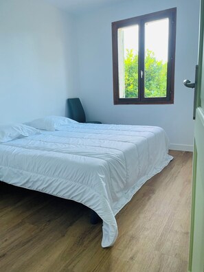 Ein Schlafzimmer mit Bett, Stuhl, Fenster und Tür.
