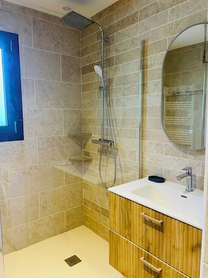 Ein Badezimmer mit Dusche, Waschbecken, Spiegel und Holzausbau.
