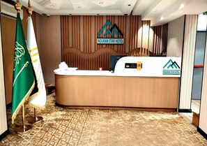 A reception desk with a logo, a flag, and a patterned carpet. - Nuran Star Serviced Apartments An Nuzhah (Jeddah)
