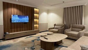 Una sala de estar moderna con un televisor de pantalla plana, dos sofás, una mesa de centro y una alfombra estampada.