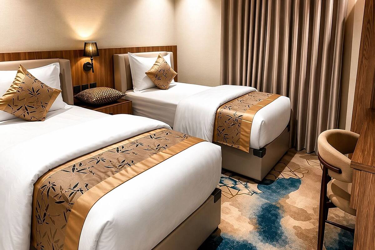 A hotel room with two beds, a desk, a chair, and a large window with curtains.