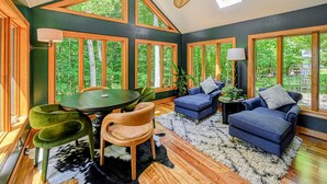 A room with large windows, a ceiling fan, a dining table with chairs, and a sofa.