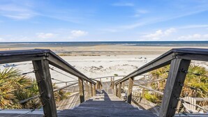 Una escalera de madera que lleva a una playa con vista despejada al océano.