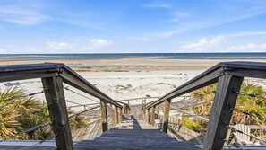 Eine Holztreppe führt zu einem Strand mit freiem Blick auf das Meer.