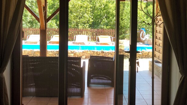 An outdoor patio with wicker furniture, a pool, and a wooden fence.