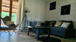 A living room with a sofa, a chair, a coffee table, a floor lamp, and a wall-mounted fan.