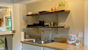 Una cocina con armarios blancos, encimera de madera, fregadero e iluminación empotrada.