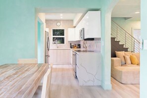 A modern kitchen with a marble countertop, wooden cabinets, and a built-in oven. - Design District House (Miami)