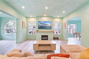 A living room with a fireplace, a television, and a view of the outdoors. - Design District House (Miami)
