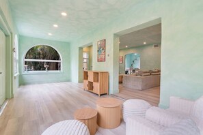 A spacious room with a large window, a wooden cabinet, a round wooden table, and a white sofa. - Design District House (Miami)