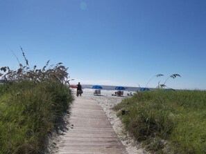 A wooden pathway leading to beach umbrellas and a sandy beach. - 188 Twin Oaks newly back on rental program. Enjoy views of the Harbourtown Links Golf Course and sunsets over Calibouge Sound (Hilton Head Island)