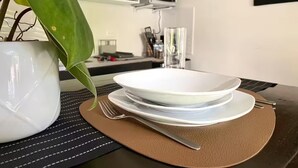 Ruokapöydällä on valkoinen lautanen, haarukka ja veitsi ruskean aluslakanan päällä.