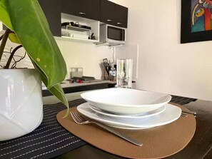 A dining table with a white plate, a fork, and a knife on a brown placemat. - Studio with a private garden | Within walking distance of the UCA district (Antiguo Cuscatlan)