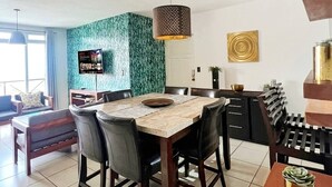 Een moderne woonkamer met een eethoek, een televisie en een groene accentmuur.