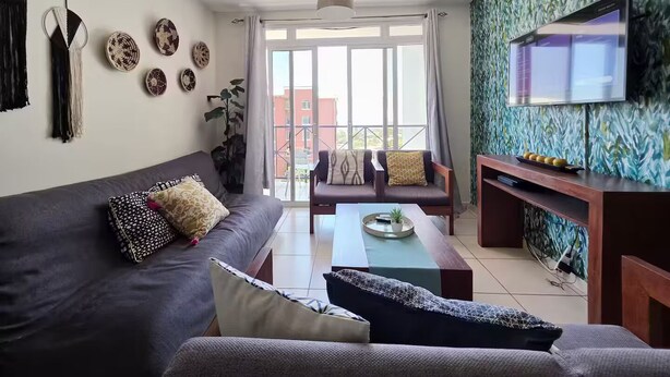 Een moderne woonkamer met een bank, salontafel, televisie en decoratieve wanddecoraties.